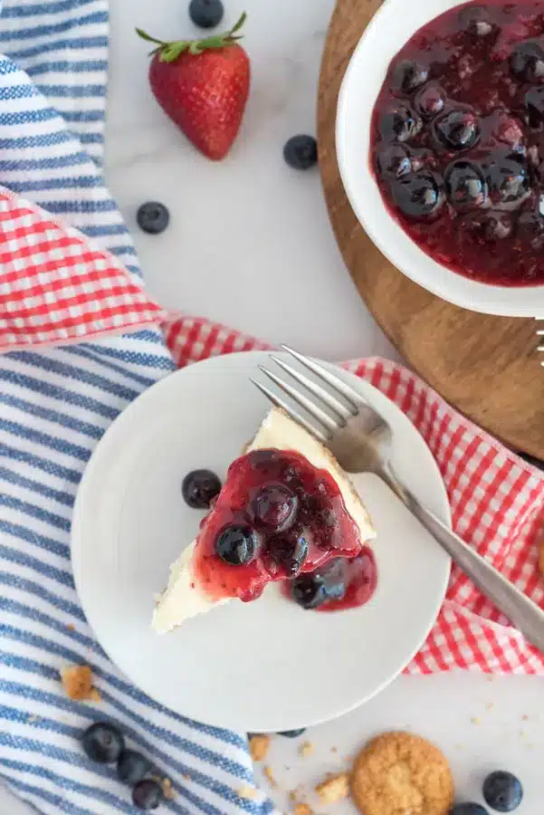 Slice of red, white, and blue Instant Pot cheesecake on a white saucer.
