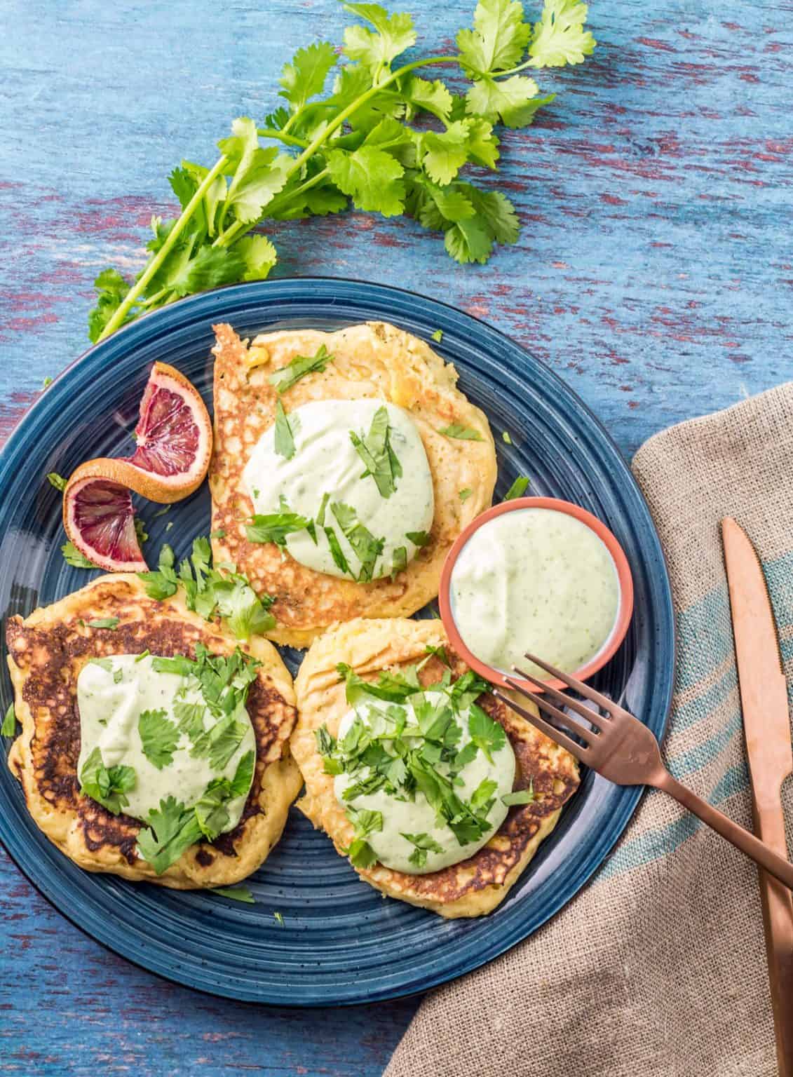 Savory masa pancakes on a blue plate with sauce and cilantro.