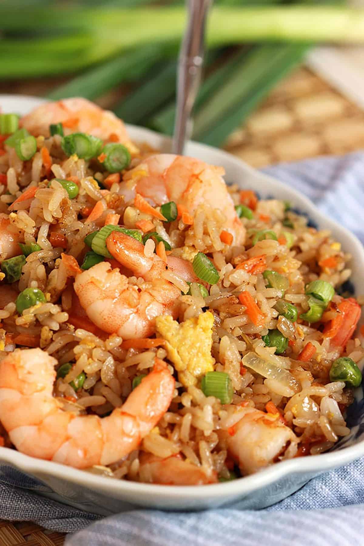 Bowl full of shrimp fried rice with a spoon in the background.