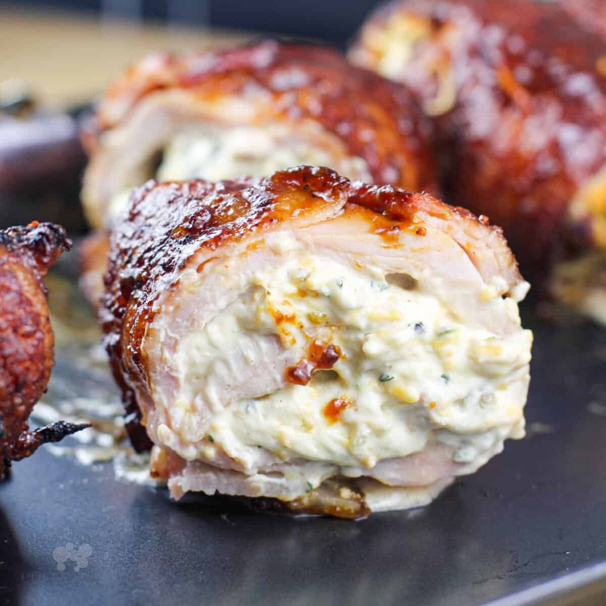 Jalapeno stuffed chicken bombs sliced open on a dark surface.