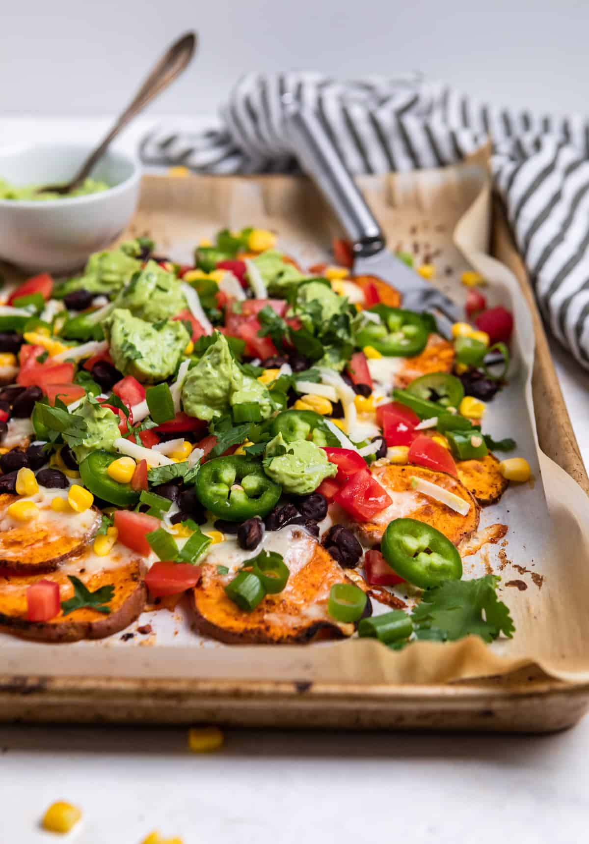 Sweet potato nachos with toppings on a sheet pan.