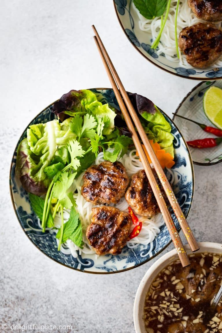 Meatballs with noodles and lettuce in a bowl with chopsticks.