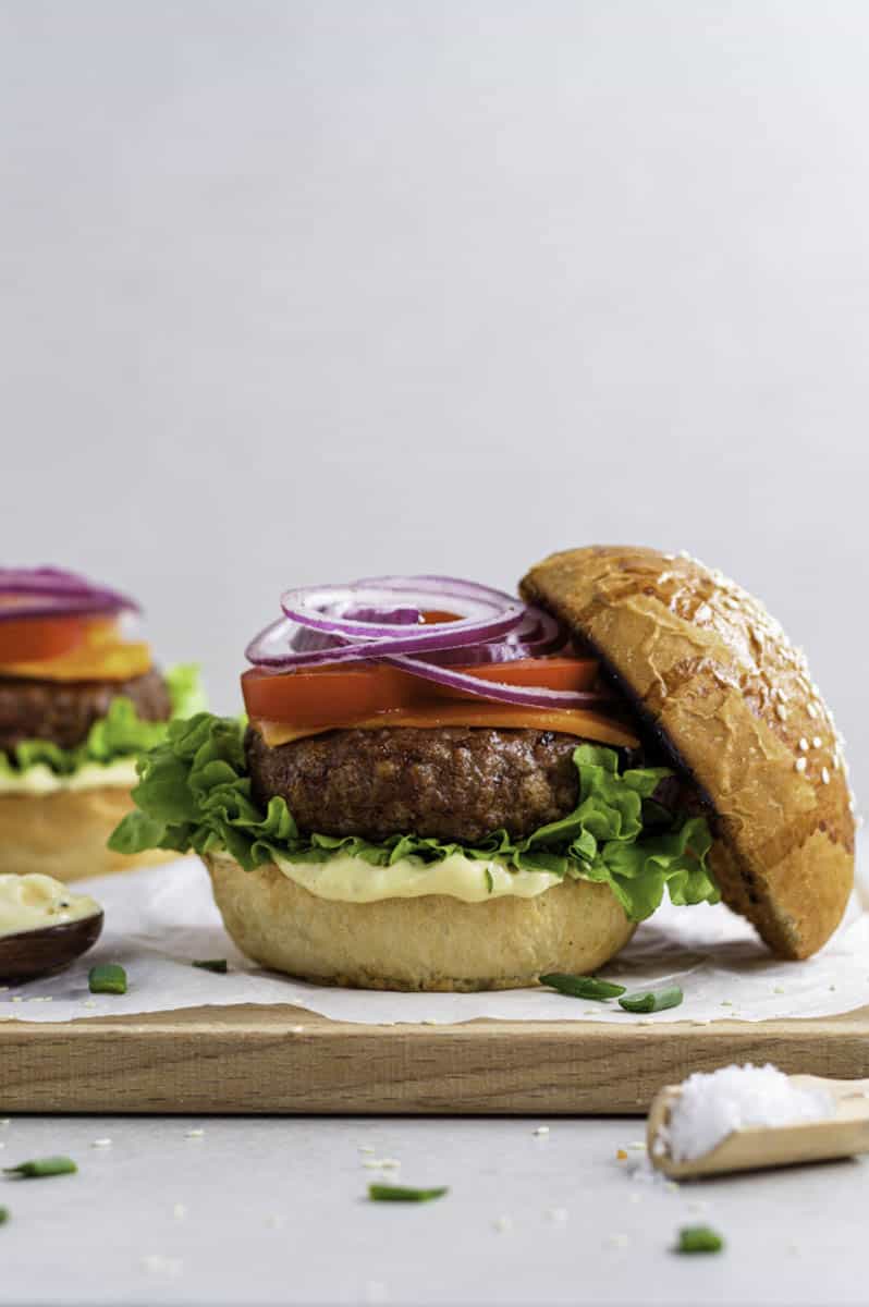 Beyond burger with red onion, tomato, cheese and lettuce on a sesame seed bun.