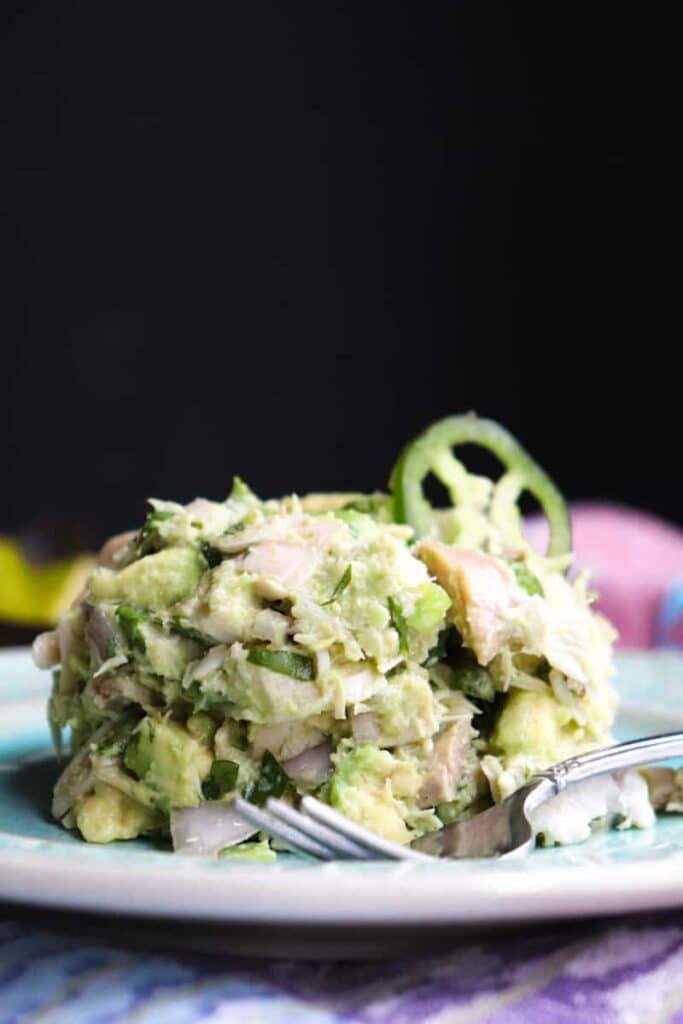 Avocado chicken salad with a fork on a light colored plate.