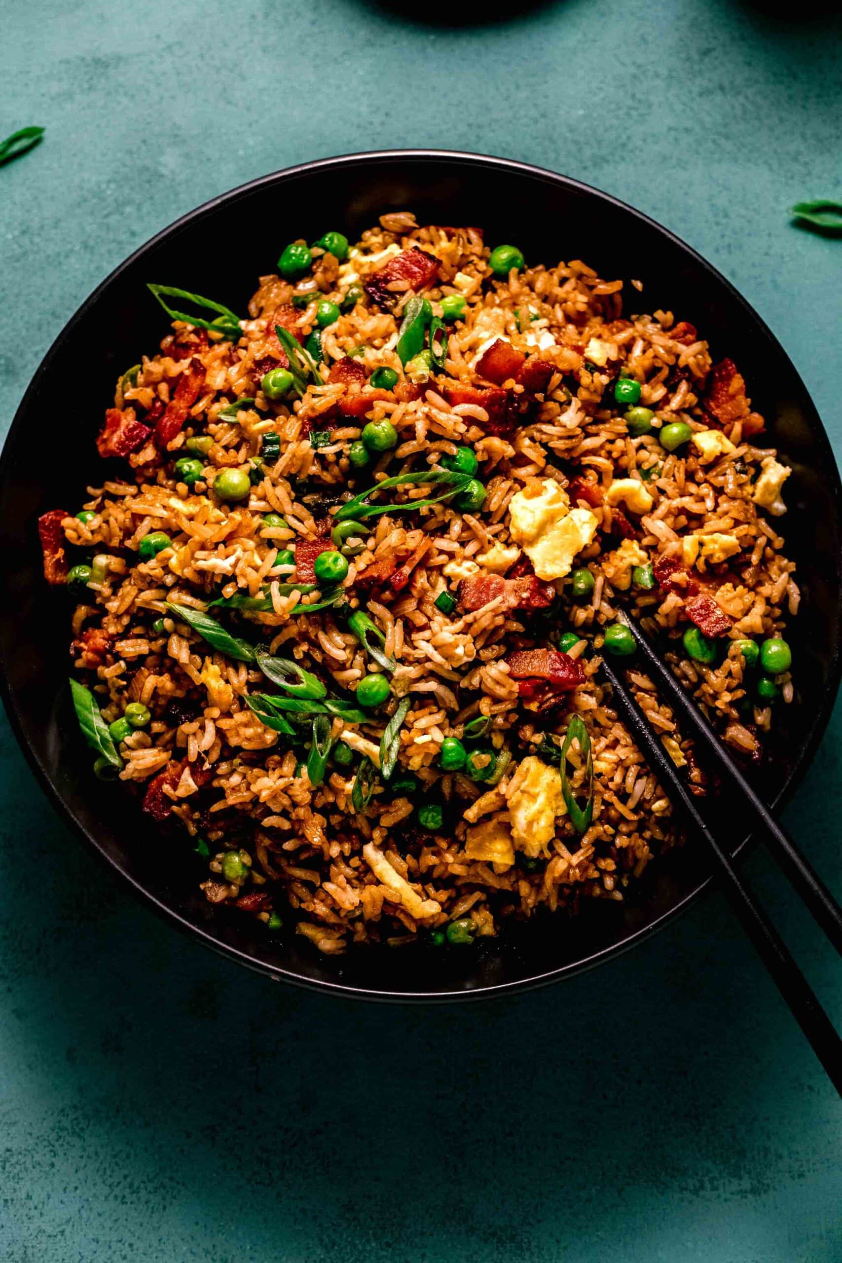 Bacon fried rice on a black plate.