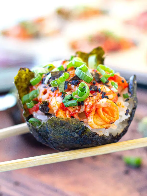 Baked sushi cup held with chopsticks.