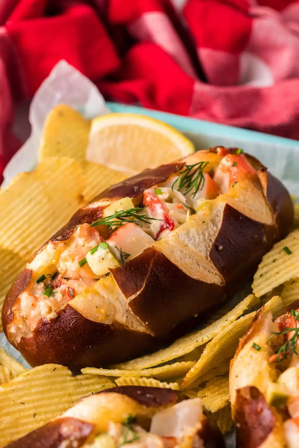 Lobster salad in a pretzel roll with chips.