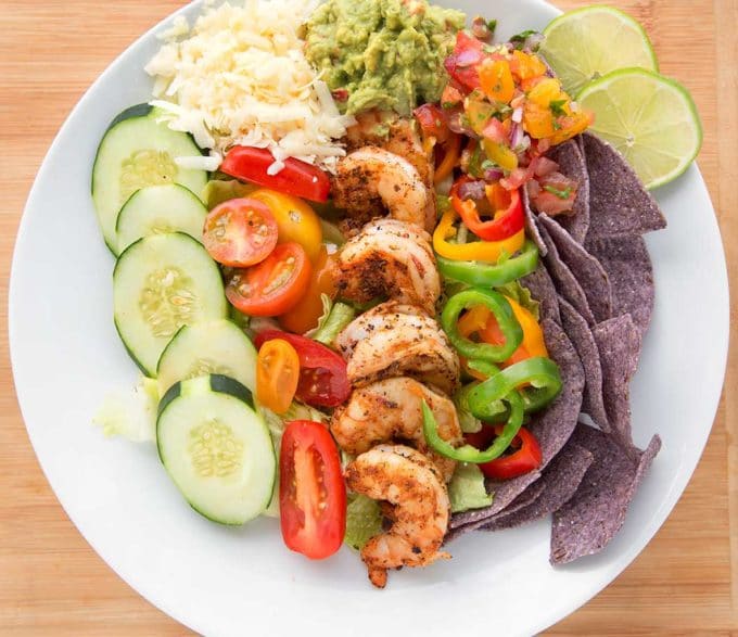 White plate full of blackened shrimp nachos ingredients.