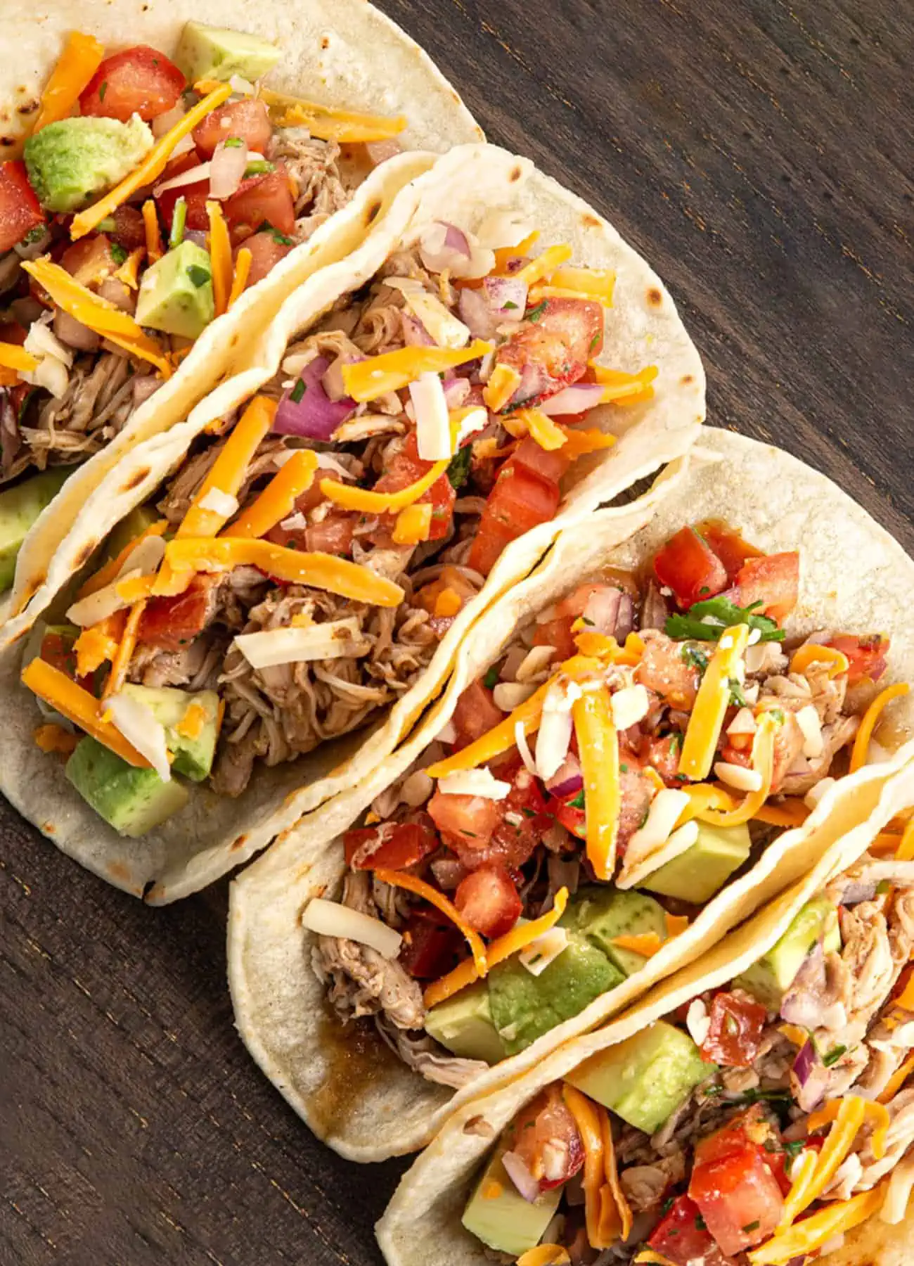 Chicken tacos loaded with delicious toppings on a wooden surface.