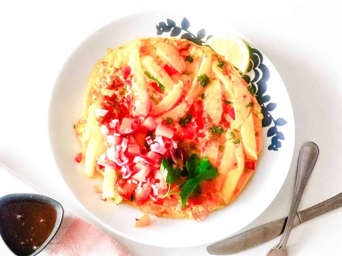 Fries and eggs omelette on a decorative plate.