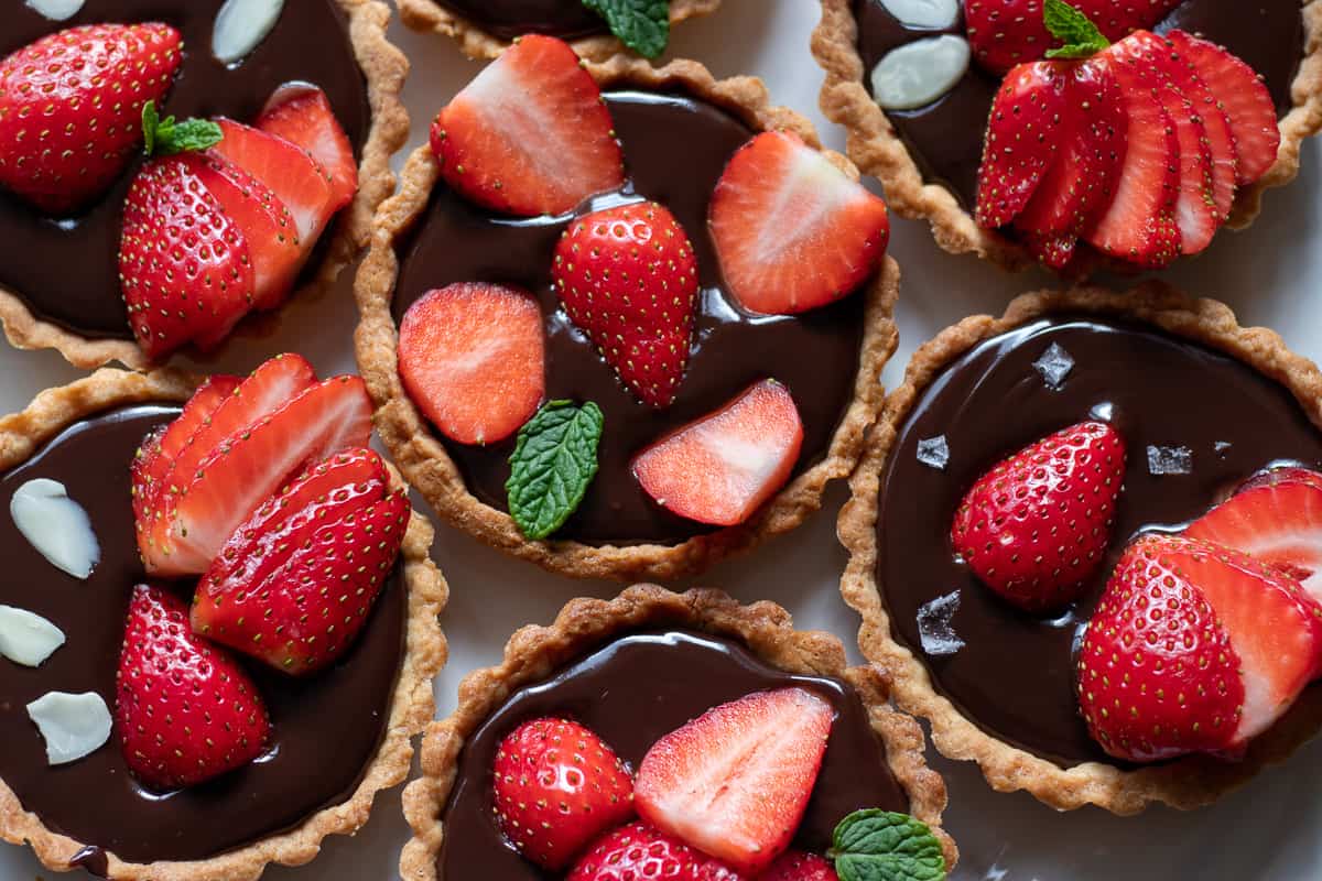 Mini chocolate tarts with sliced strawberries on top.