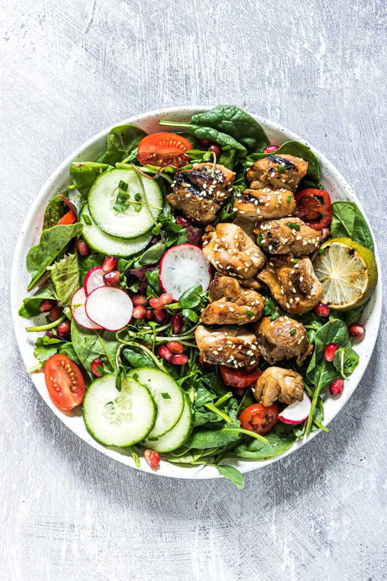 Coconut grilled chicken salad with veggies in a white bowl.