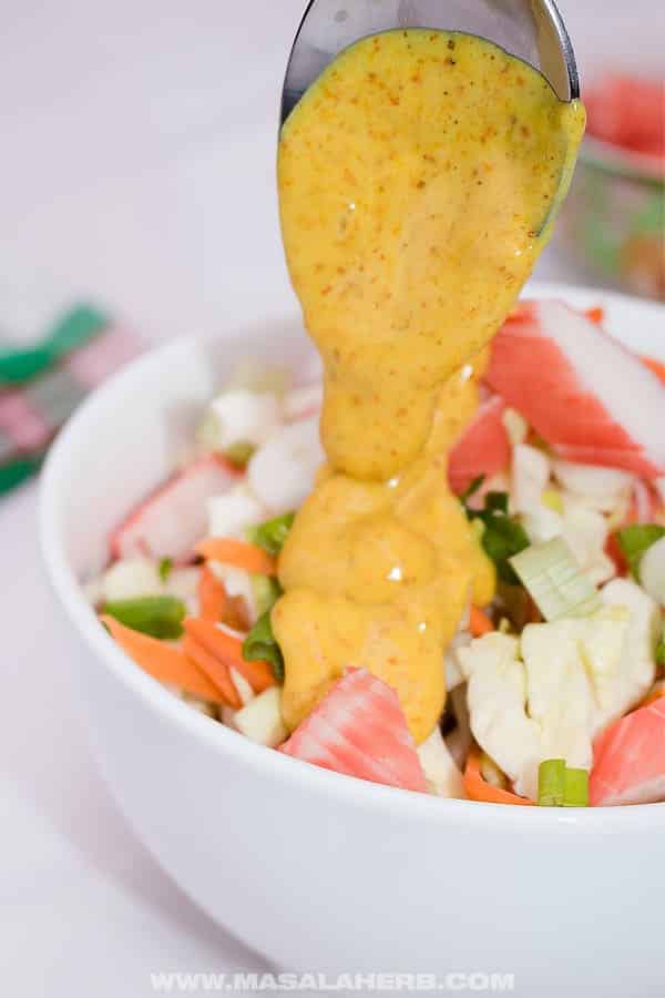 Crab salad with spoon pouring sauce.