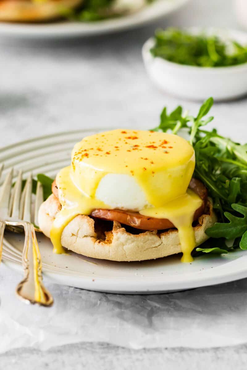 Classic eggs benedict on a plate with arugula.