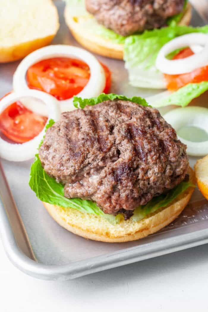 Elk burger with lettuce, onion, tomato on bun.