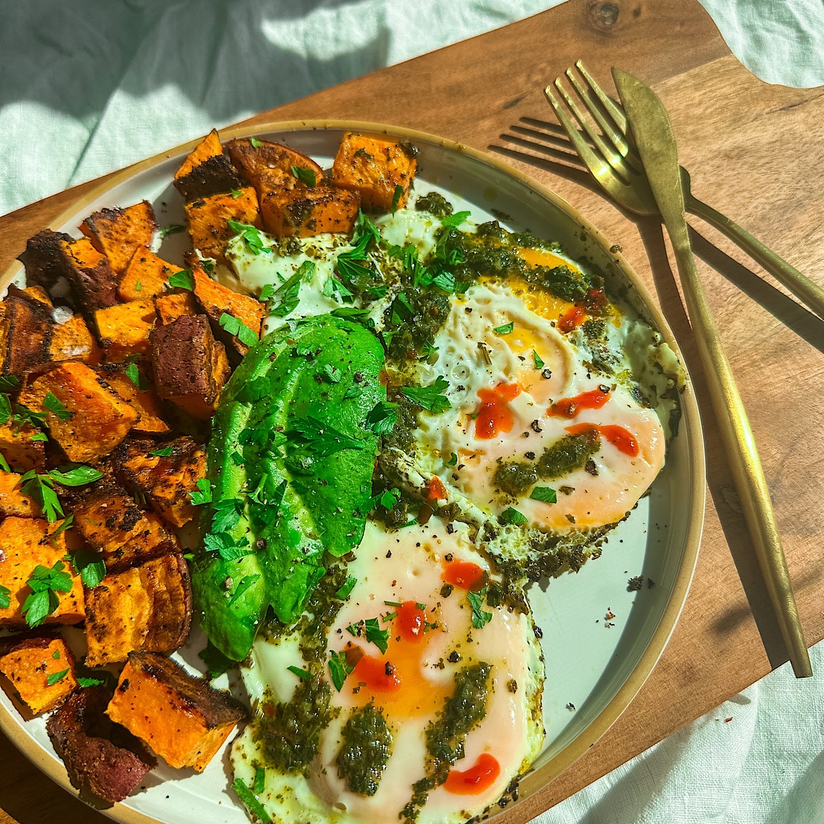 Plate with chimichurri fried eggs, sweet potatoes, and avocado.