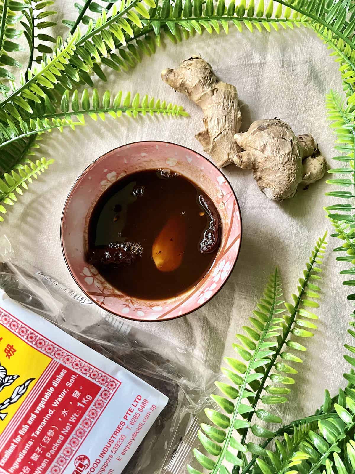 Bowl full of tamarind sauce with ginger on the side.