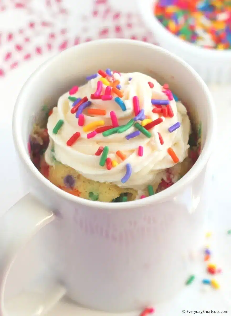 Closeup of funfetti mug cake with frosting and sprinkles.