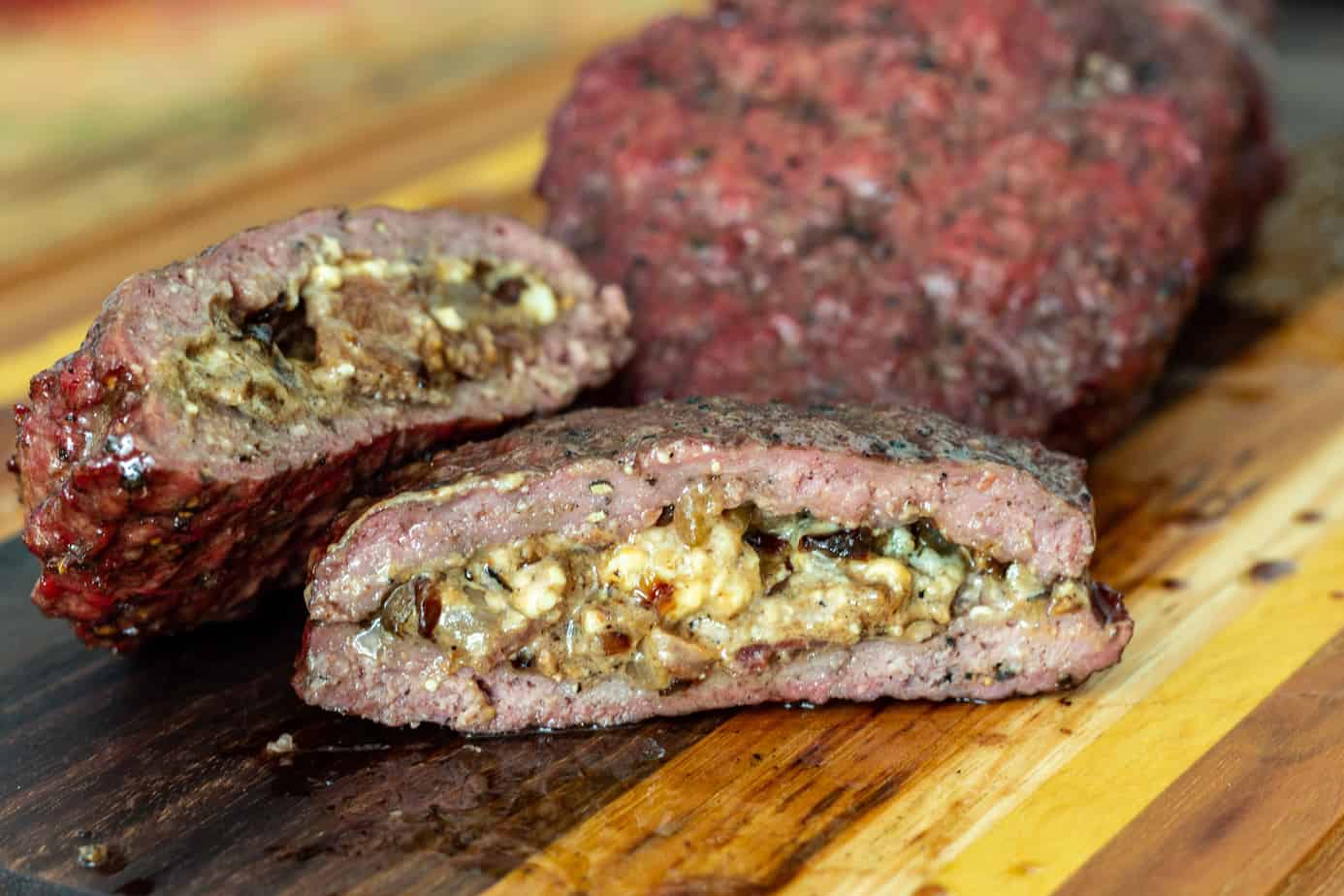 Stuffed juicy lucy burger on a wooden cutting board.
