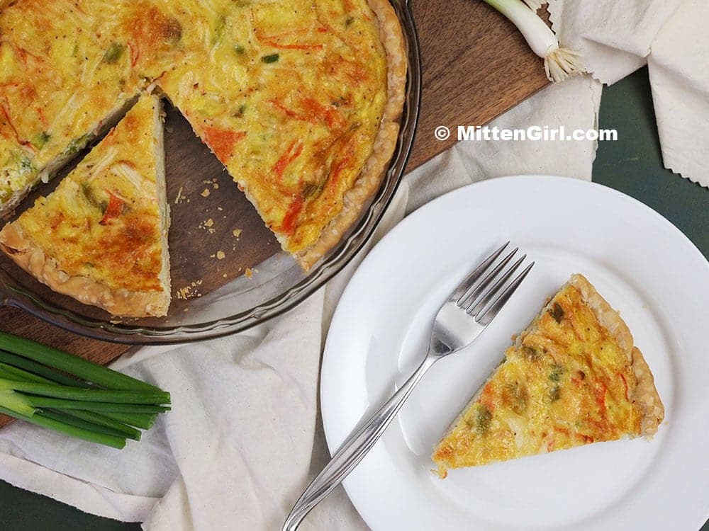 Slice of crab quiche on a white plate.