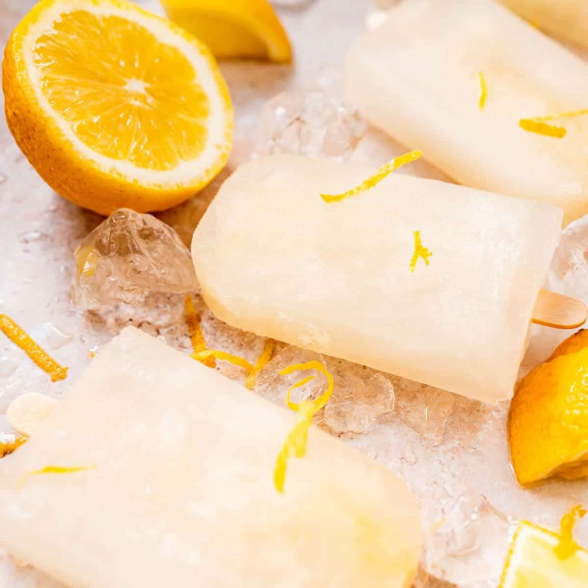 Lemon popsicles over ice on a sheet pan.