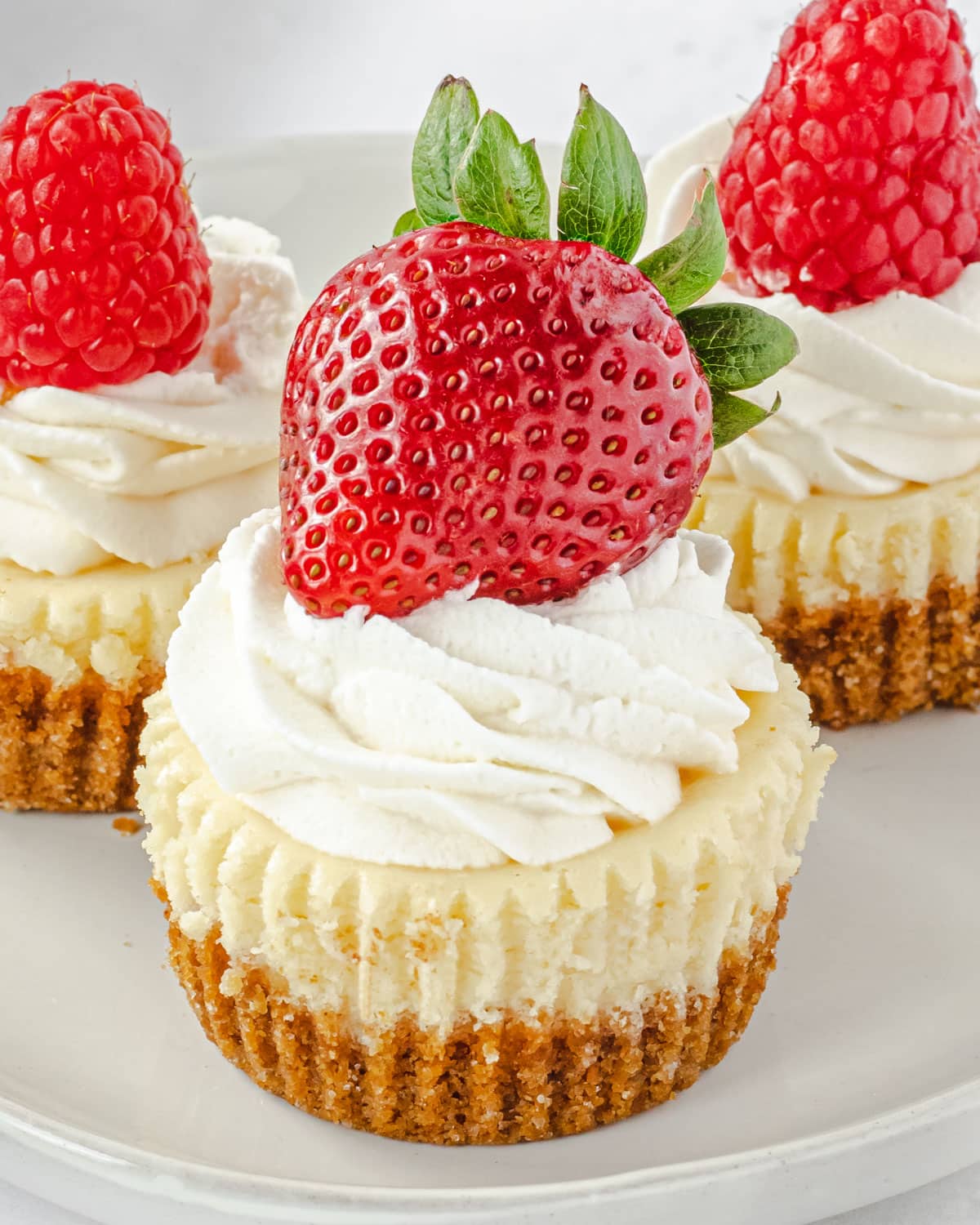 Mini cheesecakes with whipped cream and a whole strawberry.