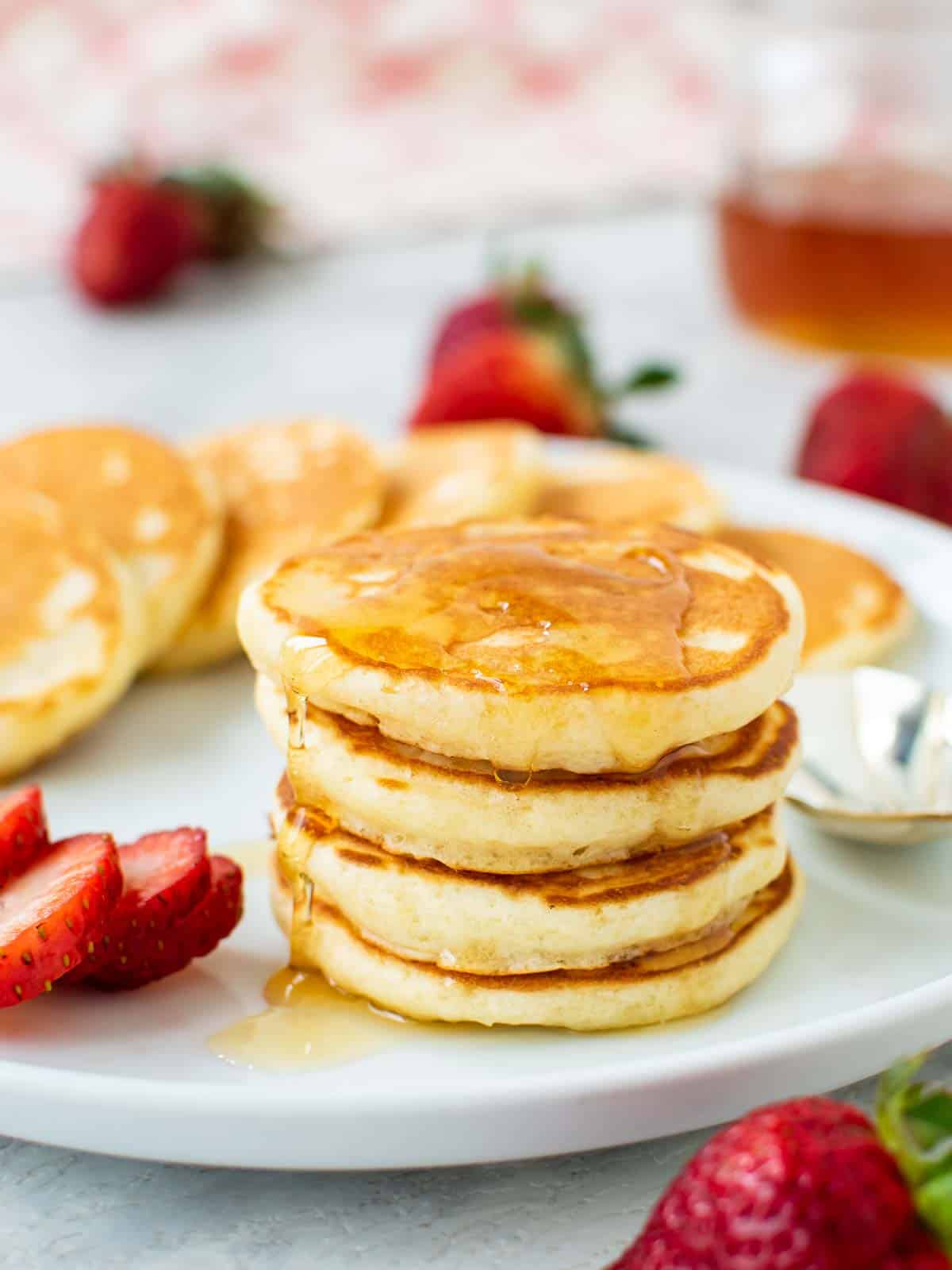 Stack of mini pancakes on a white plate.