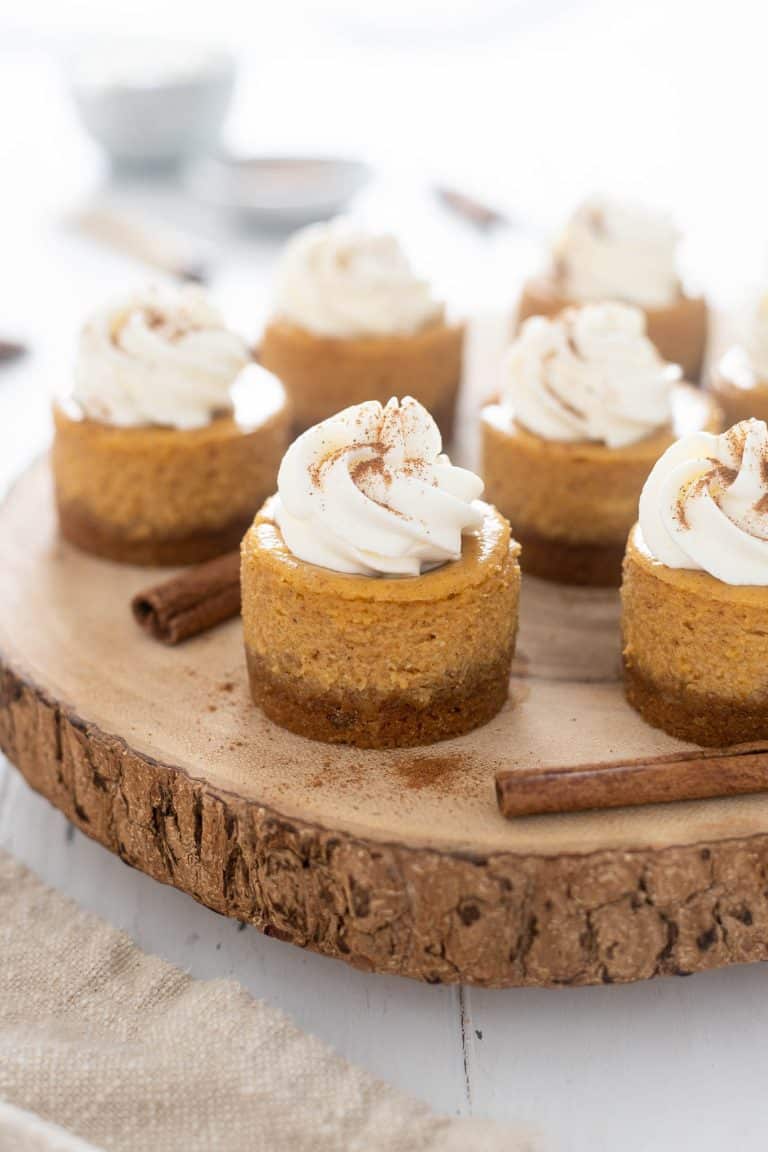 Mini pumpkin cheesecakes on a wood surface.