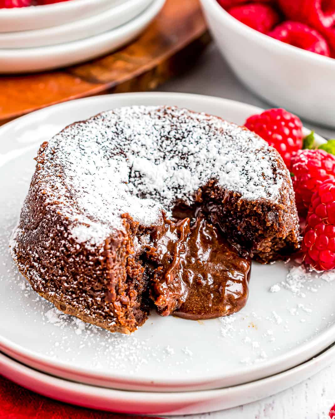 Molten chocolate cake on a white plate with raspberries.