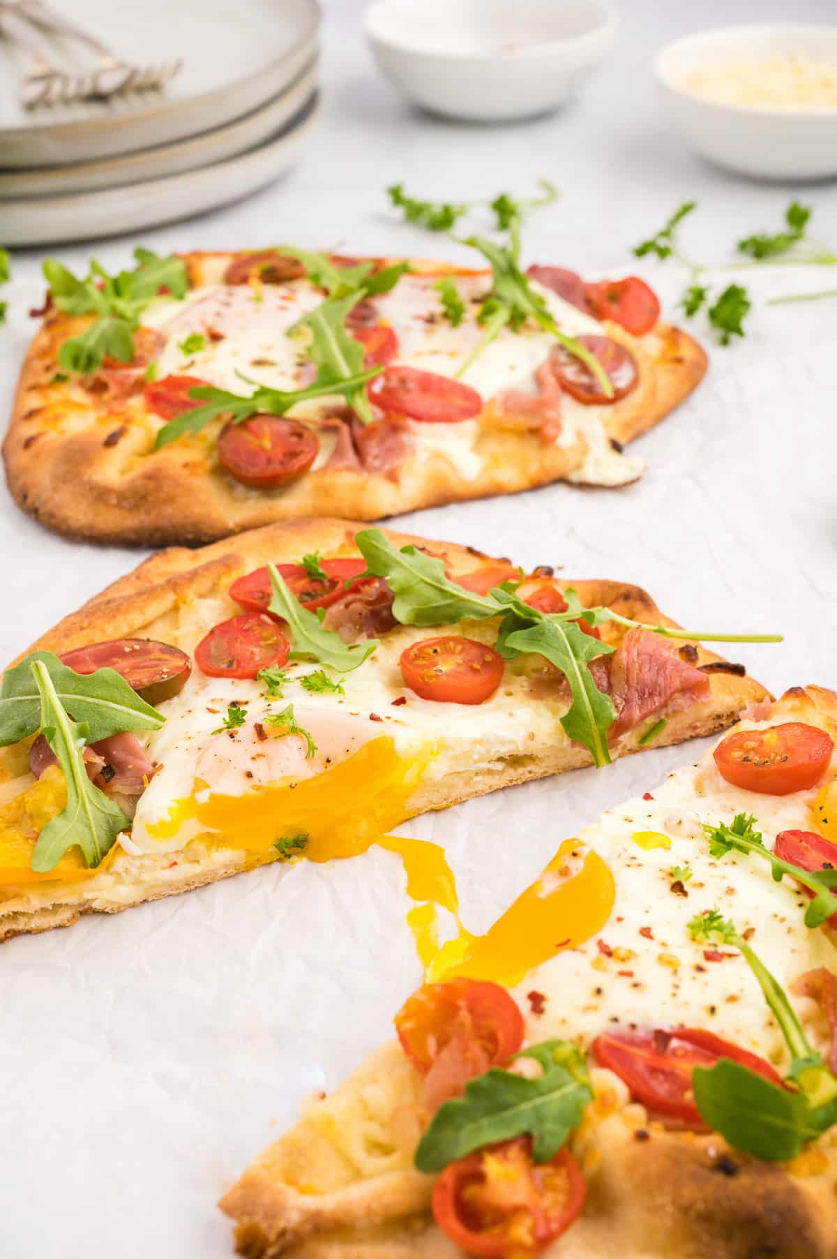 Breakfast pizza with tomatoes, arugula, egg, and bacon.