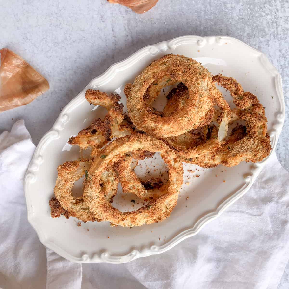 Crispy oven baked onion rings on a white platter.