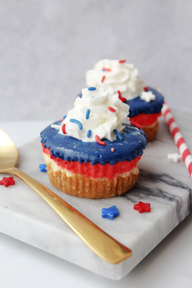 Patriotic, red, white, and blue styled mini cheesecakes on a marble slab.