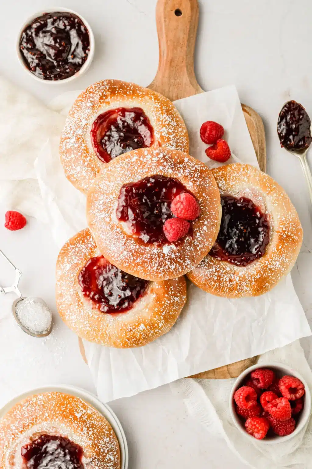 Wooden serving board with raspberry cheesecake brioche buns.