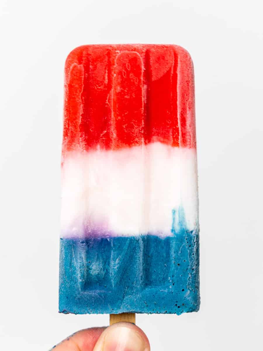 Hand holding red, white, and blue popsicle.