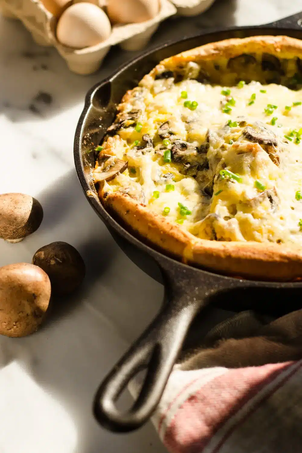 Savory Dutch baby puff pancake in a cast iron with ingredients surrounding it.