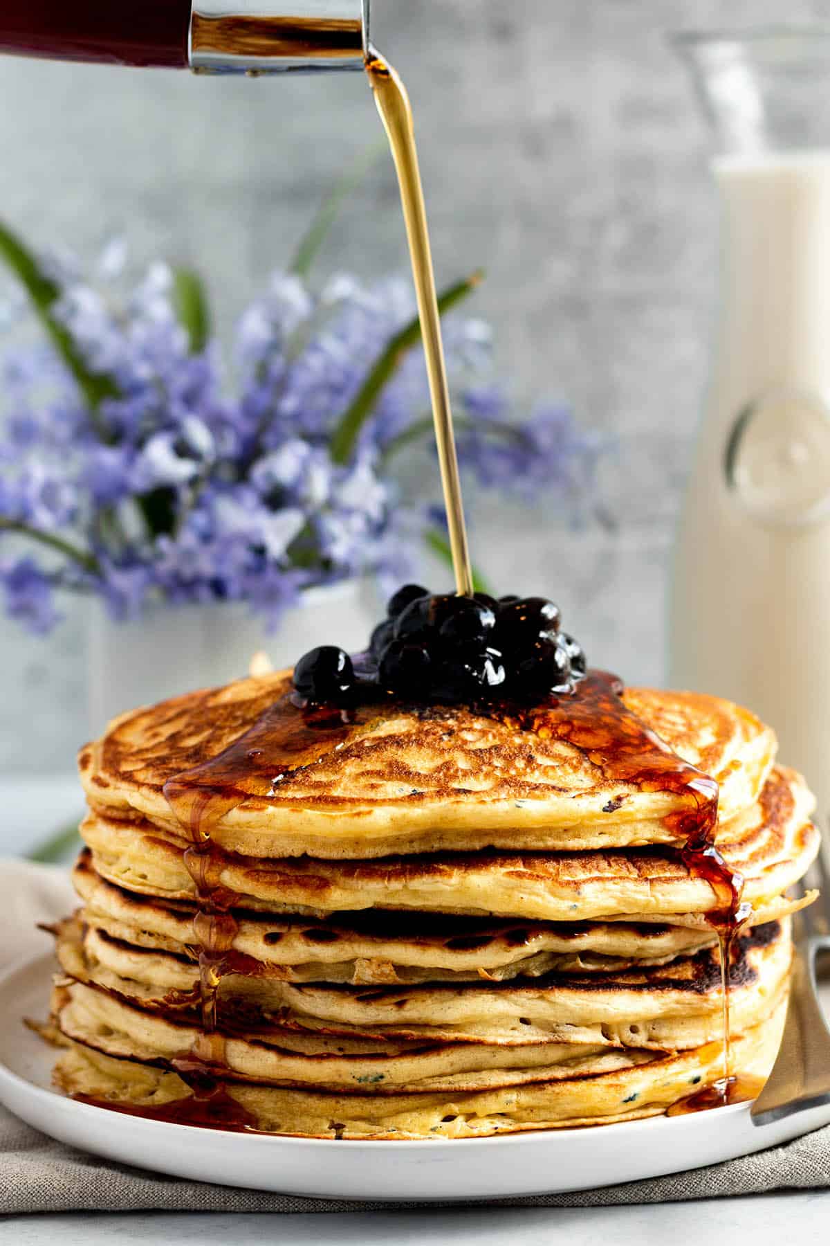 Syrup poured on a stack of blueberry topped sourdough pancakes.