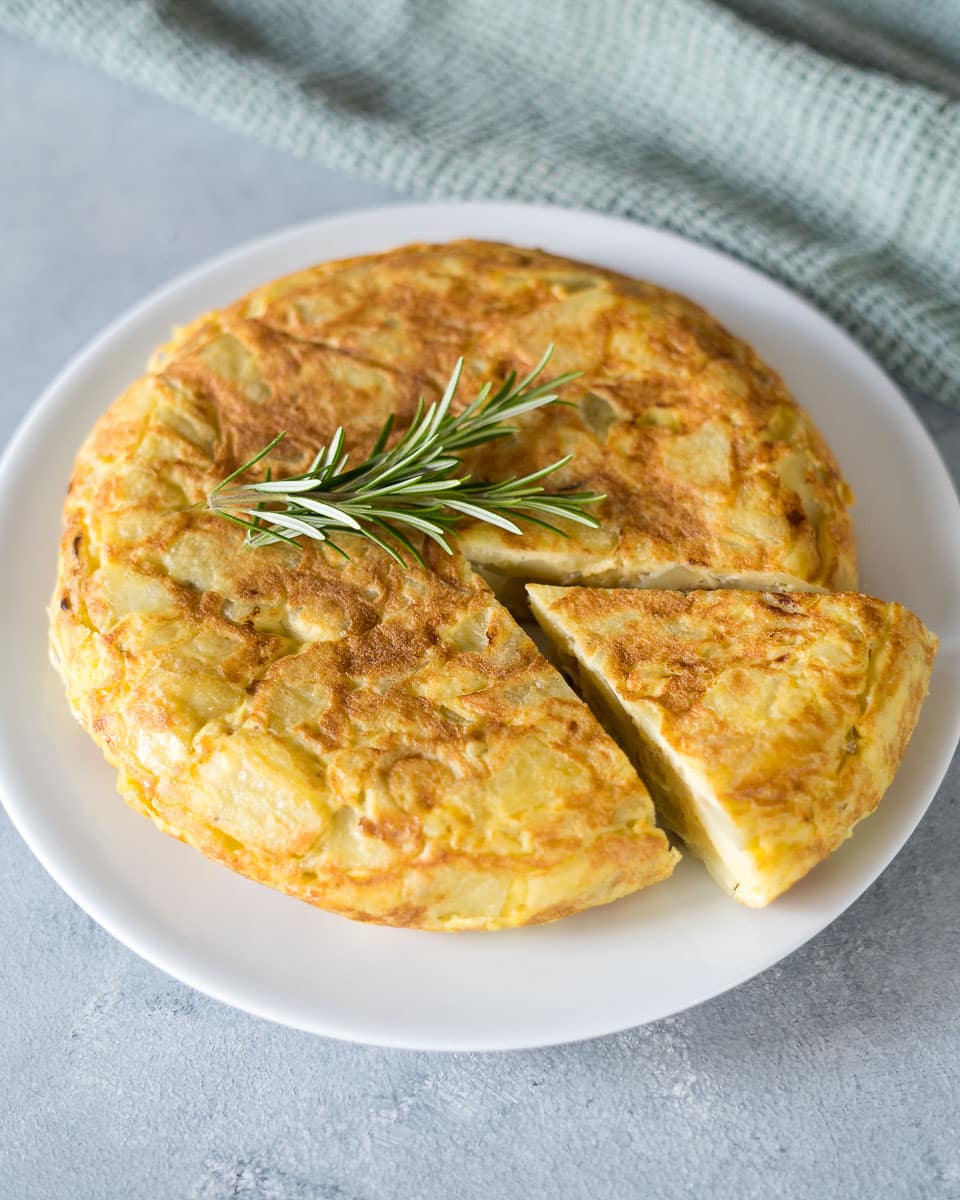 Spanish omelet on a plate with rosemary.