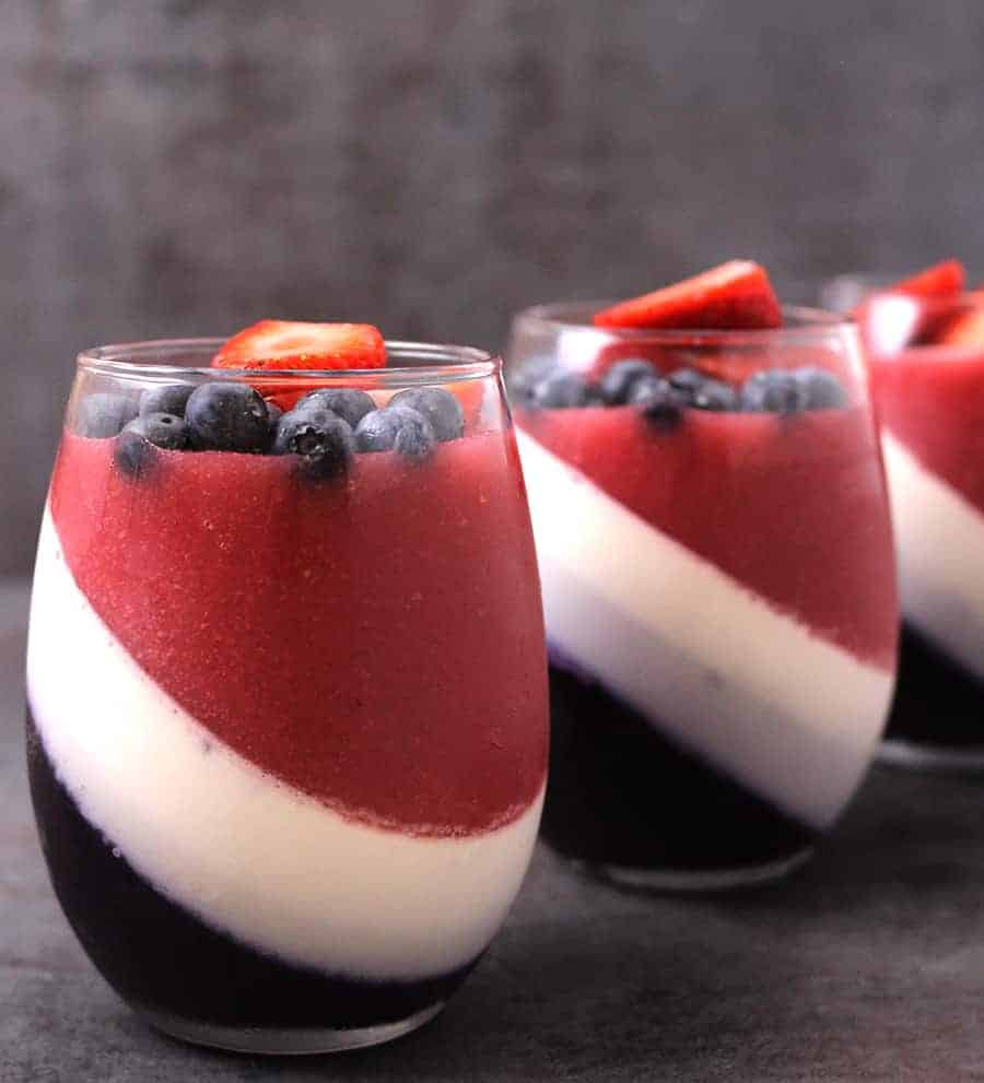 Three glasses of beautiful strawberry and blueberry panna cotta.