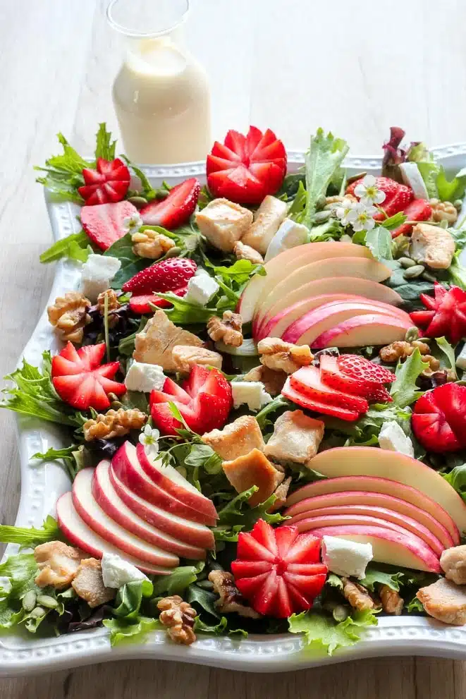 Strawberry chicken salad with creamy maple dressing on a large white decorative plate.