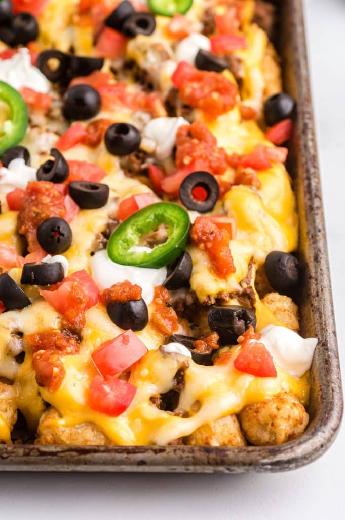 Close up of loaded tater tot nachos on a sheet pan.