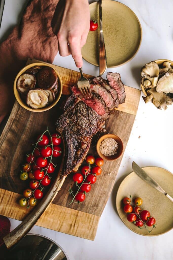 Sliced tomahawk steak on a cutting board.