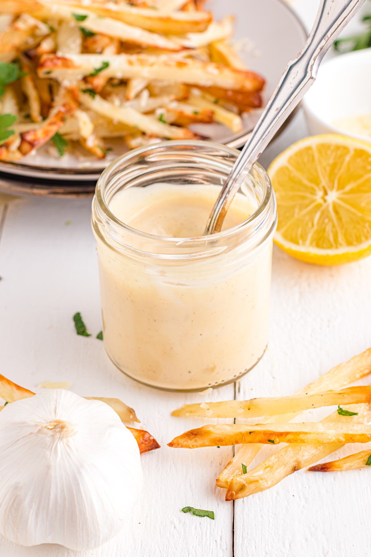 Small jar full of truffle aioli with fries in the background.