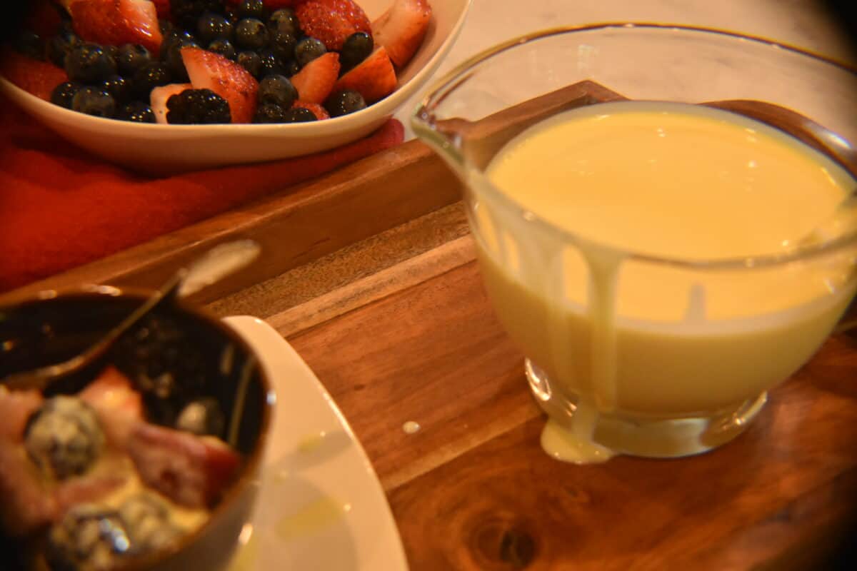 Vanilla custard sauce with berries on a cutting board.