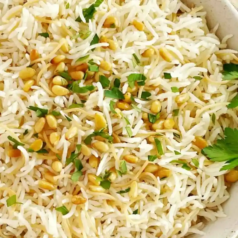 Close up of vermicelli rice topped with pine nuts and herbs.