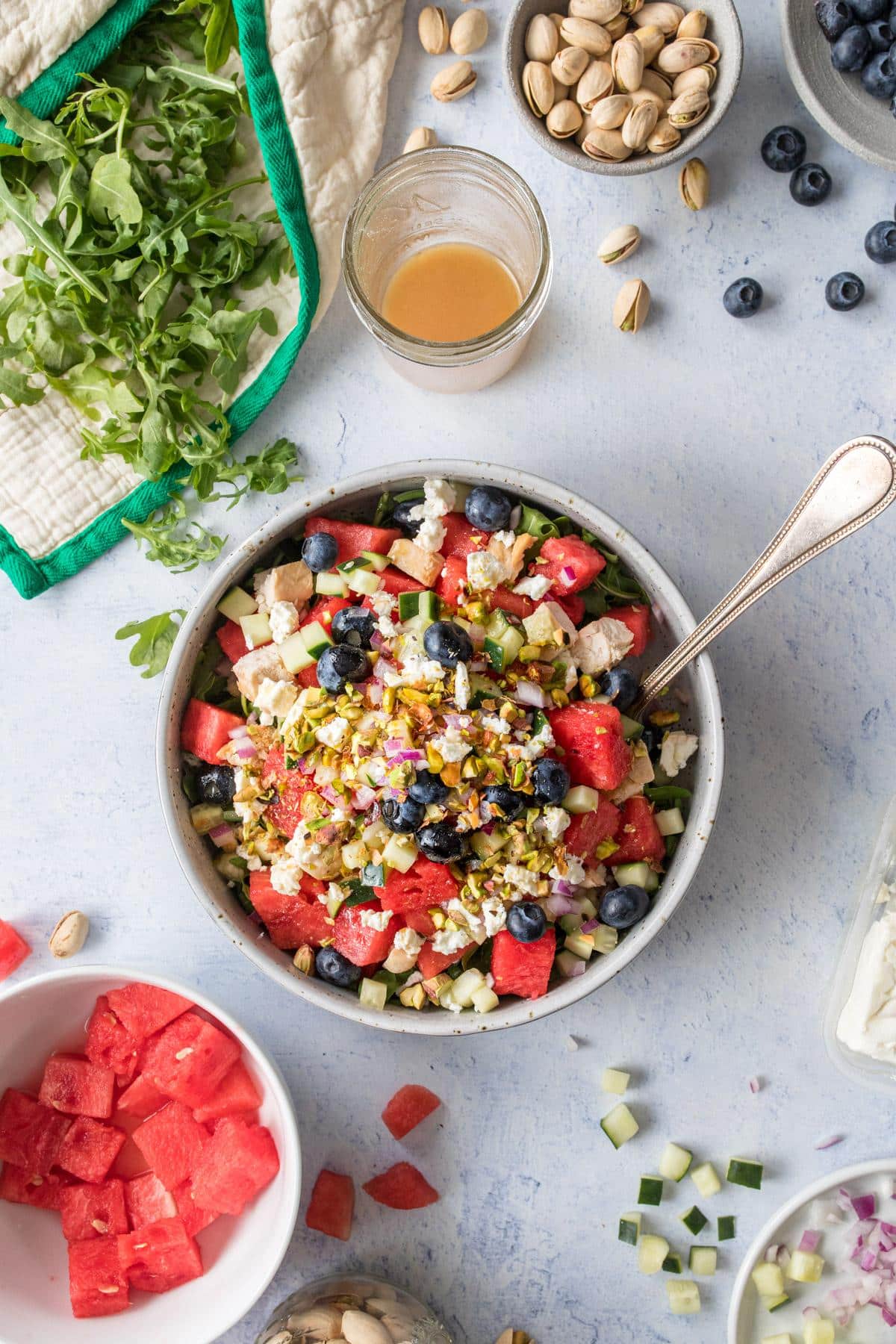 Bowl full of watermelon chicken salad with crushed pistachios, blueberries, and other vegetables.