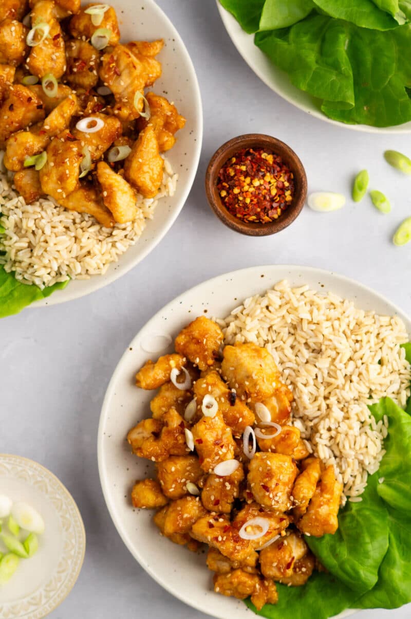 Orange chicken, rice, and lettuce on a white plate.