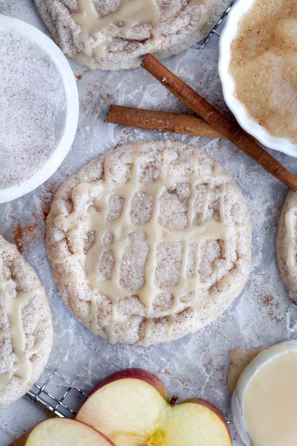 Apple cinnamon cookies on a parchment lined cooling rack  with ingredients surrounding it.