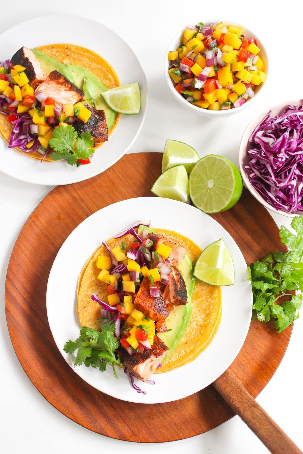 Colorful blackened salmon tacos on a white plate.