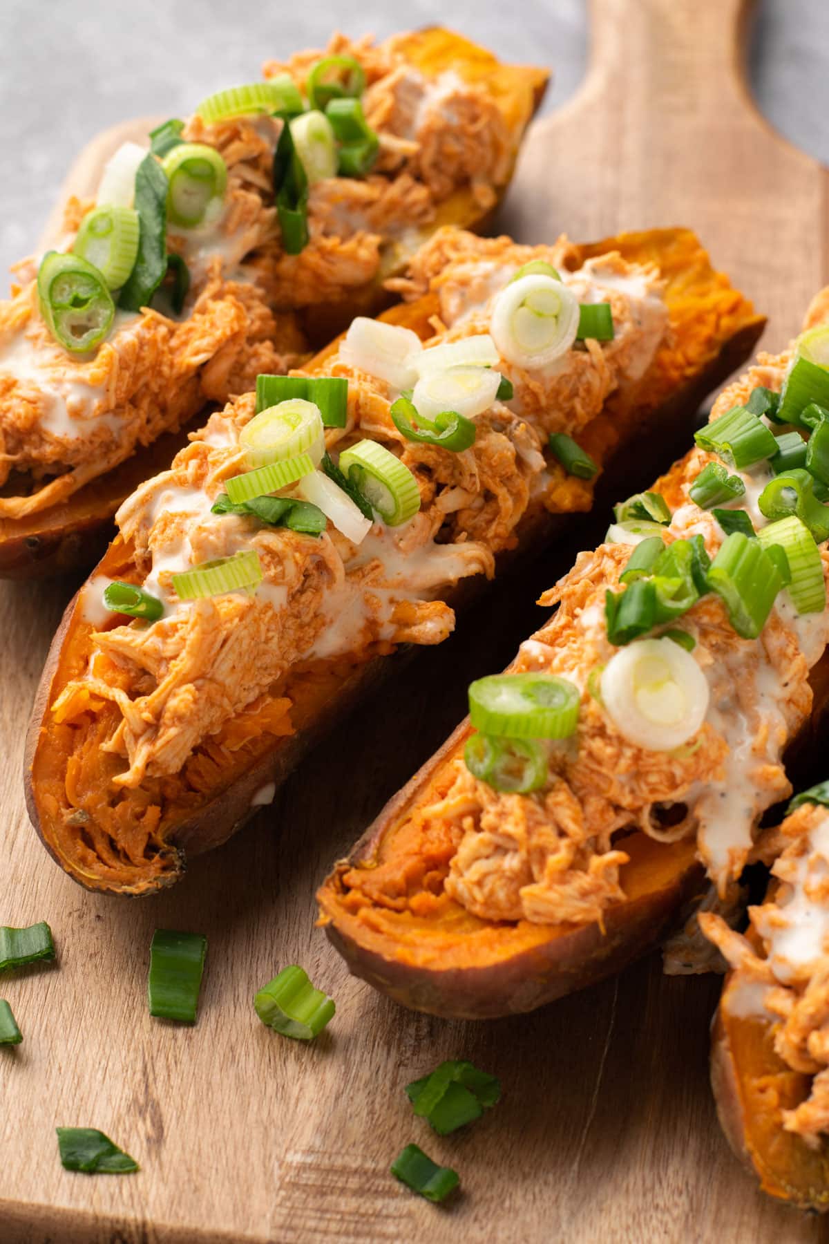 Buffalo chicken stuffed sweet potatoes on a cutting board.