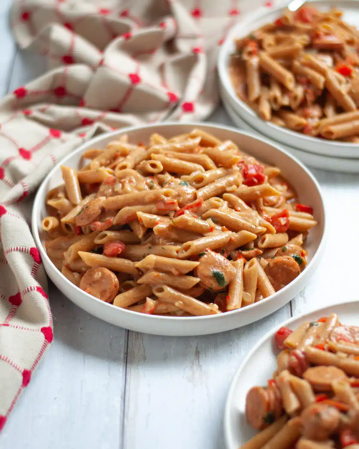 Creamy Cajun pasta with sausage on white plates.